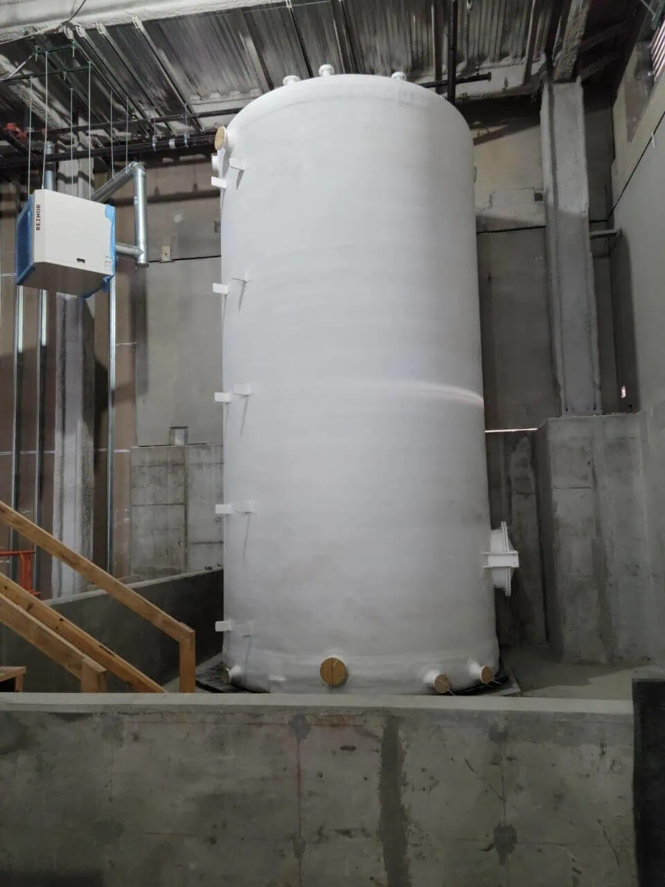 Fiberglass waste tank being installed using heavy rigging and machinery moving services.