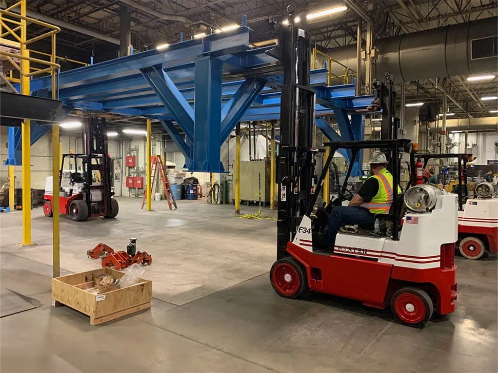 MEI Industrial Solutions crew operating heavy-duty forklifts to transport and install a 25,000 lb boiler system indoors