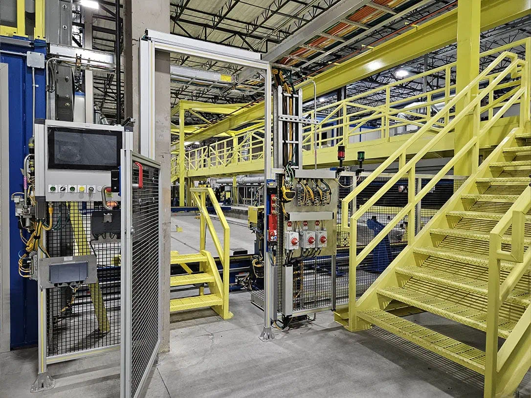 MEI Industrial Solutions millwright-installed automated industrial machinery featuring bright yellow access stairs, safety platforms, and control panels in a modern facility.